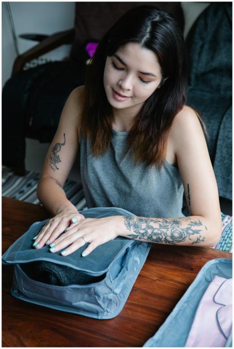 Asian woman with tattoos organizing clothes in a t