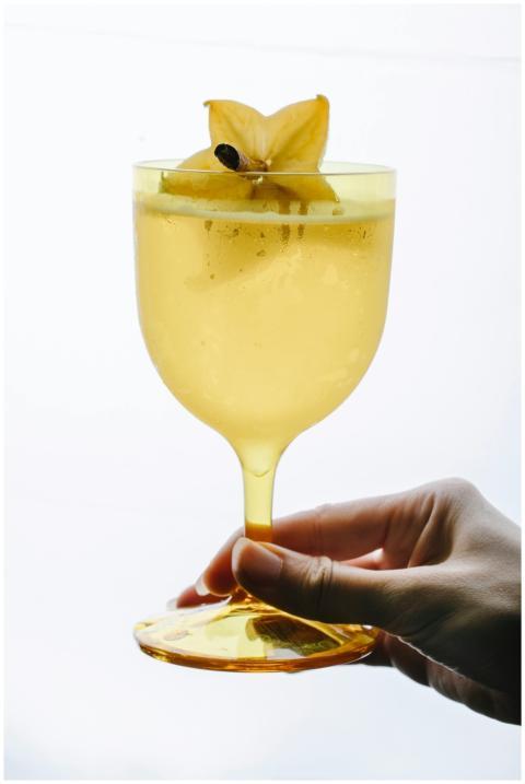 A delicious starfruit cocktail in a yellow glass,