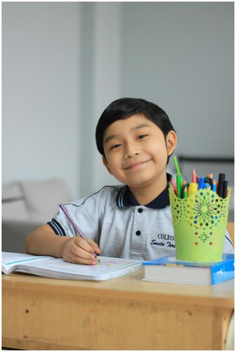 Young boy in school uniform doing homework with co