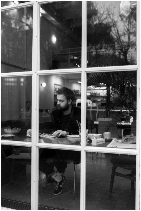 Wistful bearded man sits alone in a modern café, s