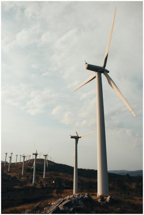 A row of tall wind turbines on a hill generating r