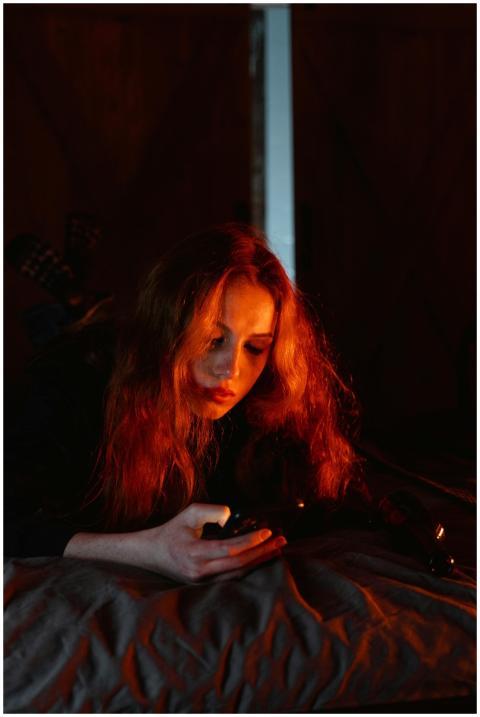 A young woman lies in a dimly lit room, focused on