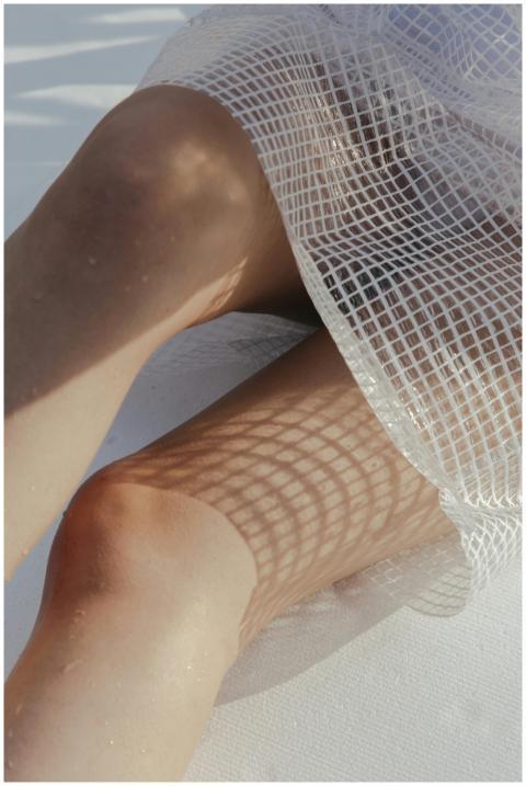 Close-up of sunlit legs with artistic mesh shadow