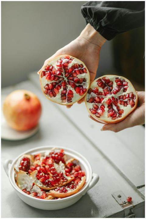 Vibrant pomegranate halves held above a bowl fill