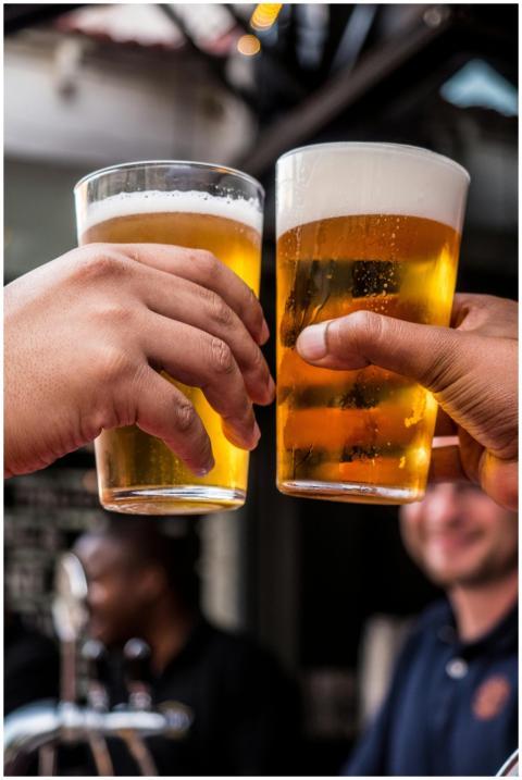 Close-up of two friends toasting with cold beer gl
