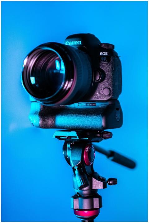 Close-up of a DSLR camera on a tripod with a blue