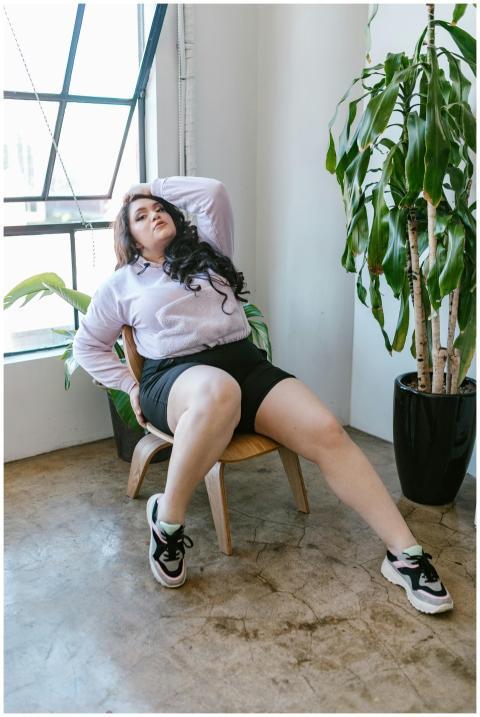 Woman sitting on a wooden chair, surrounded by ind