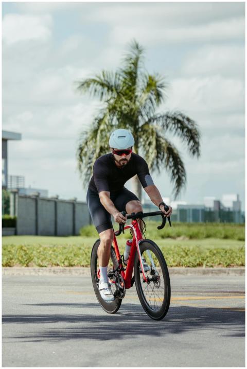 A cyclist in black apparel rides a red bicycle out