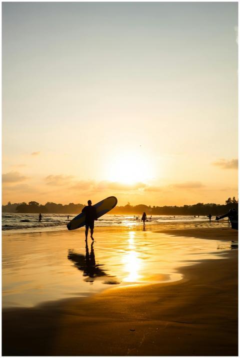 A surfer walks along Weligama Beach in Sri Lanka a