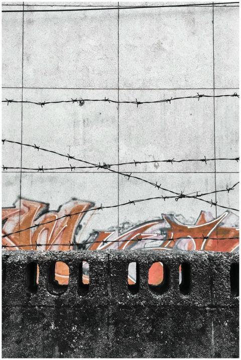 Concrete wall with colorful graffiti and barbed wi