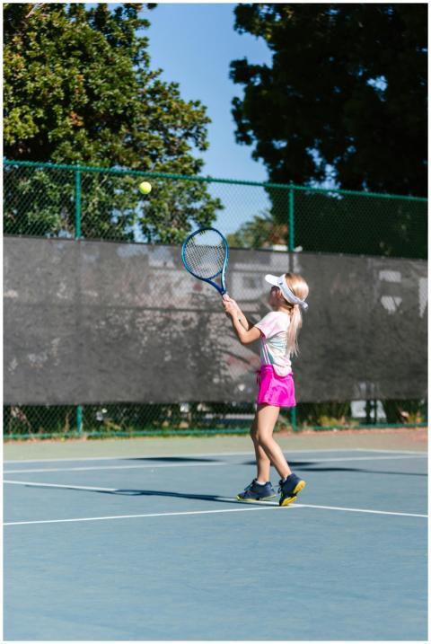 Child engages in tennis practice on an outdoor cou