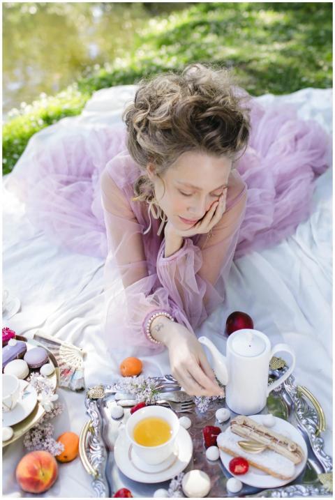A woman in a pink dress enjoying a tea picnic with