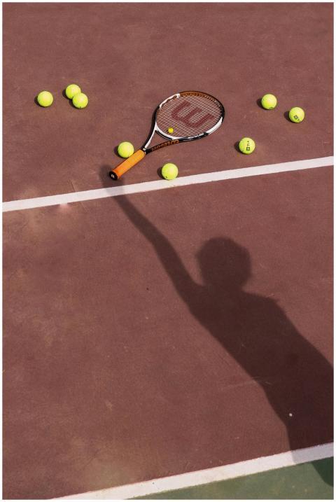 Shadow of player reaching out to tennis racket and