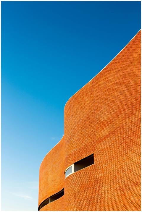 Curved brick building facade against a vibrant blu