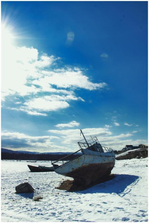 An old boat rests on a snowy shore beneath a clear