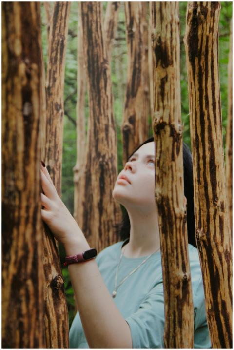 A woman in a forest looking up thoughtfully among