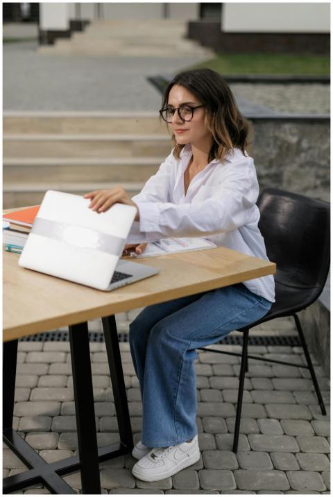 A young woman sitting outdoors, engaging in online