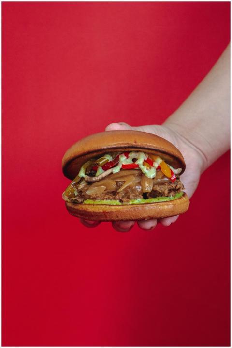 Close-up of a juicy beef burger held in hand with
