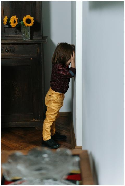 Young child standing in the corner indoors, portra