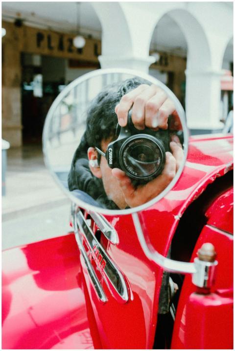 Photographer capturing reflection in vintage car m