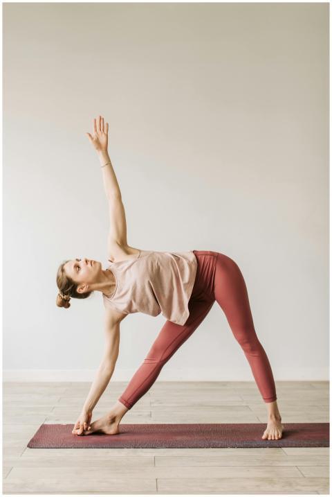 Adult woman performs a yoga pose on a mat indoors,