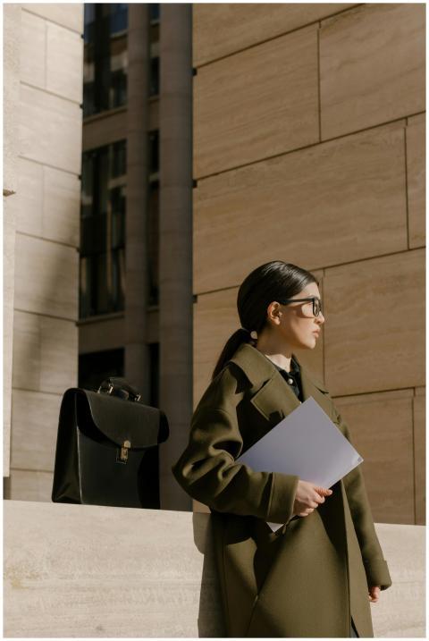 Businesswoman in a coat holding documents outside