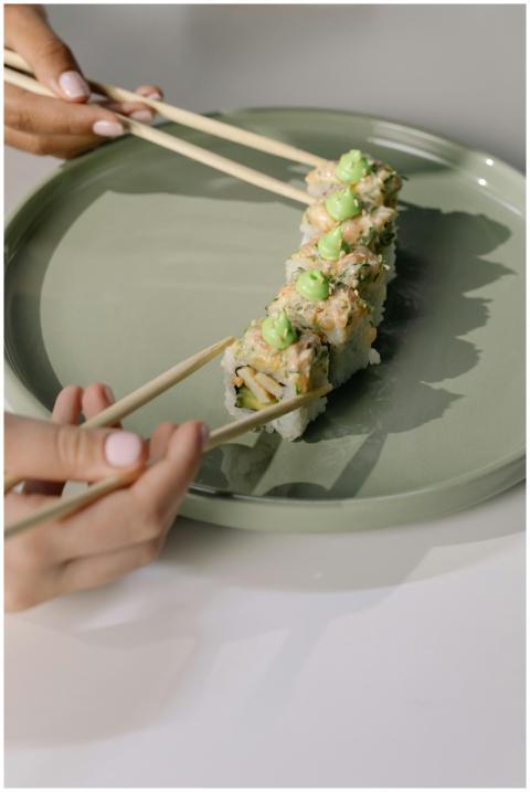 Hands delicately using chopsticks to prepare a sus