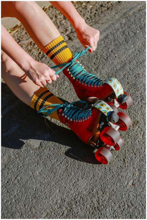 Close-up of a person tying red roller skates outdo