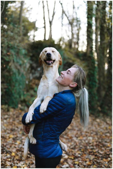 A woman joyfully hugs her Labrador Retriever in a