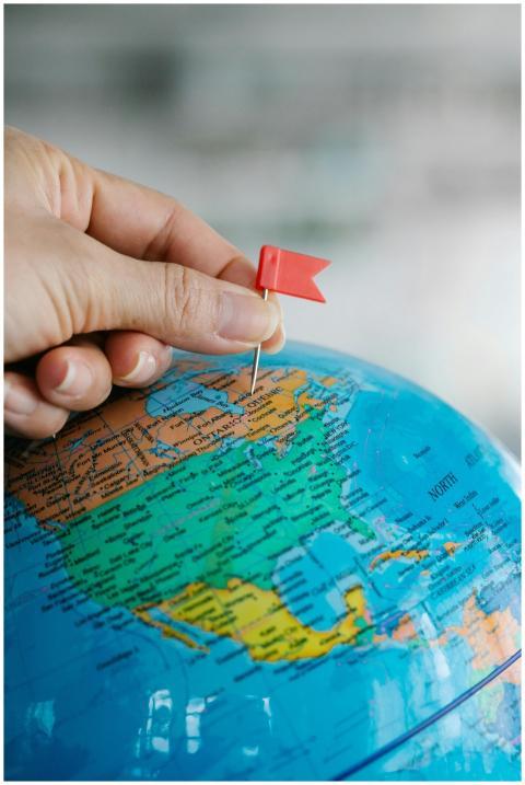 Close-up of a hand placing a red flag pin on the N