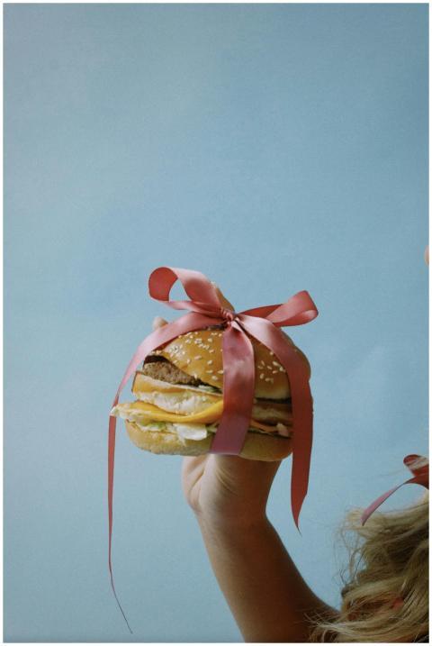Burger with pink ribbon held by child for playful