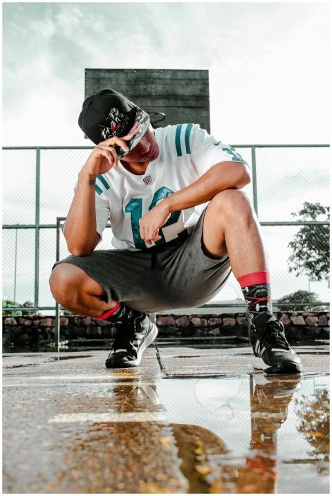 A young man in sportswear poses stylishly on a bas