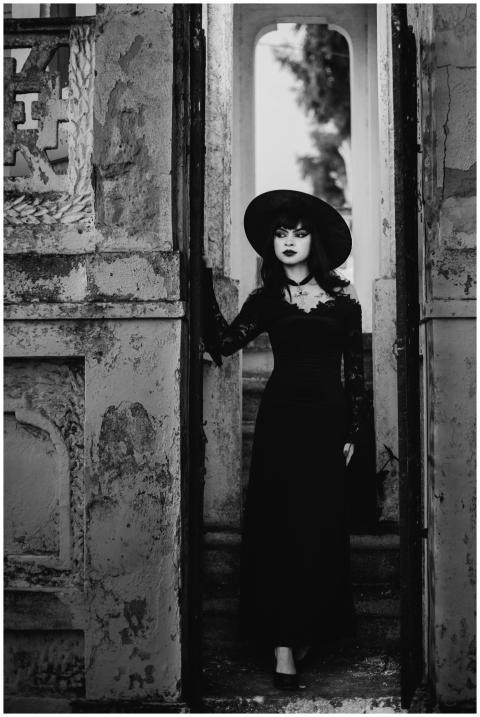Mysterious woman in gothic attire standing in an o