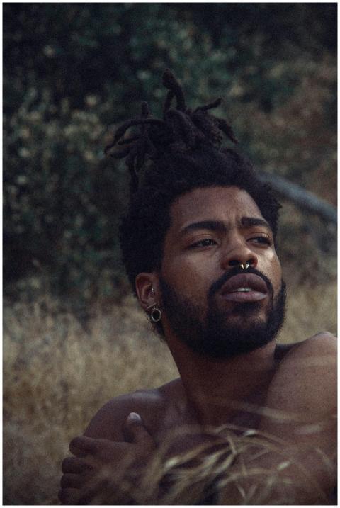 Expressive portrait of a shirtless man with dreadl