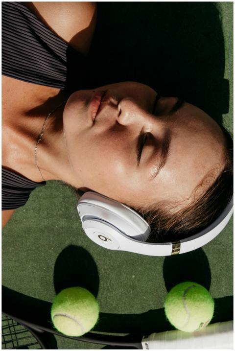 Relaxed woman on a tennis court with headphones an