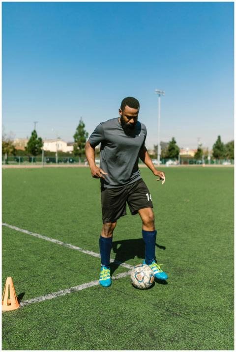 Athletic man practicing soccer skills on a sunny d