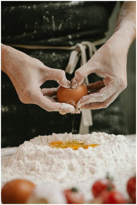Hands in flour shape dough mound cracking an egg i