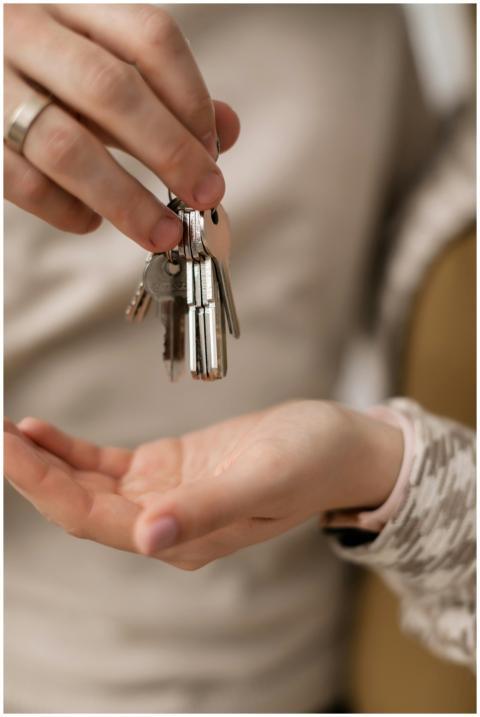 A close-up photograph of hands exchanging keys, sy