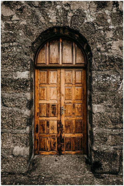 A rustic wooden door set in a textured stone wall,