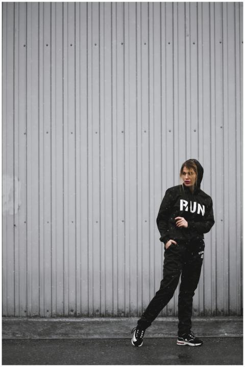 Person in black sportswear posing outdoors against