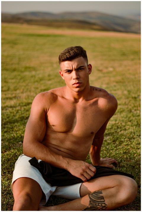 Shirtless young man with a tattoo relaxing on a gr