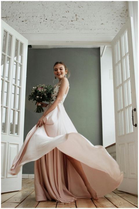 Joyful bride in an elegant gown twirling with bouq