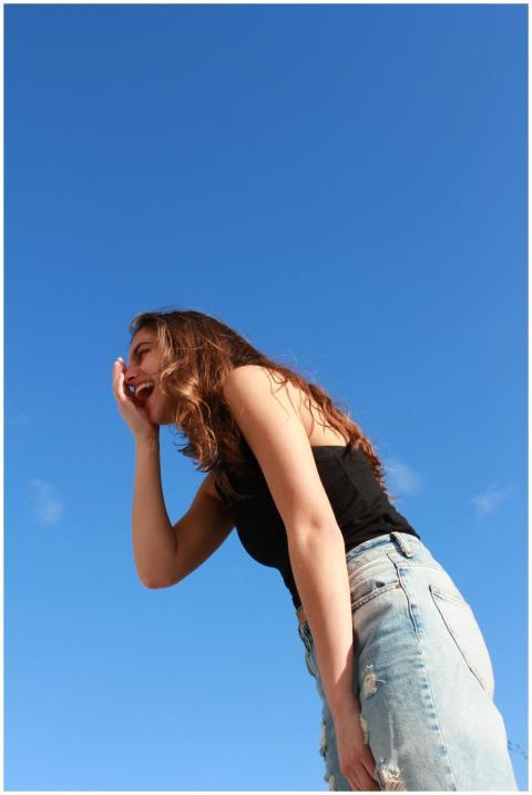 A young woman in casual attire laughing outdoors a