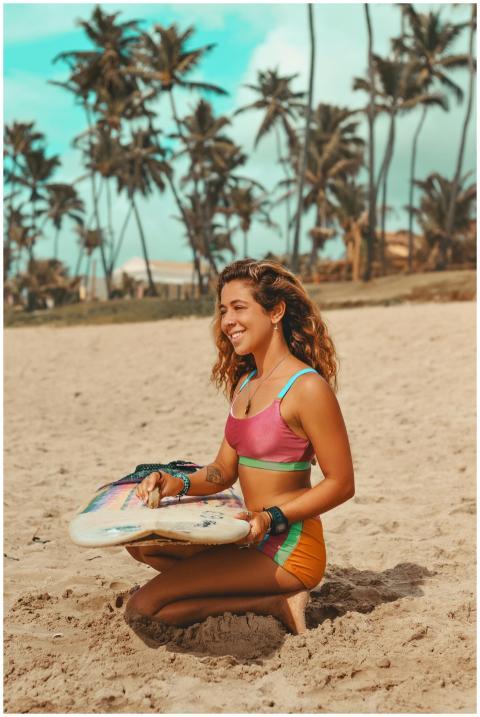 Smiling woman in colorful bikini holding surfboard