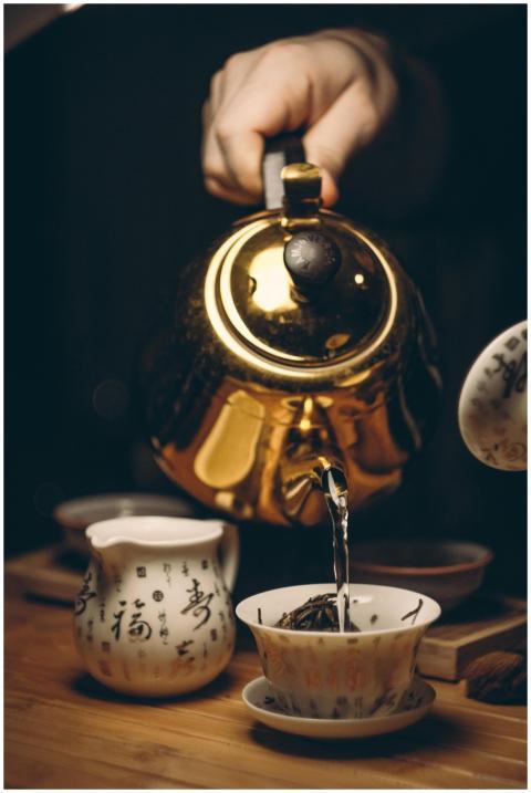 Close-up of a golden teapot pouring tea into a cup
