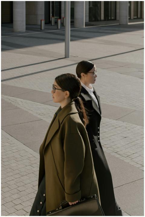 Two professional women in coats walk through an ur