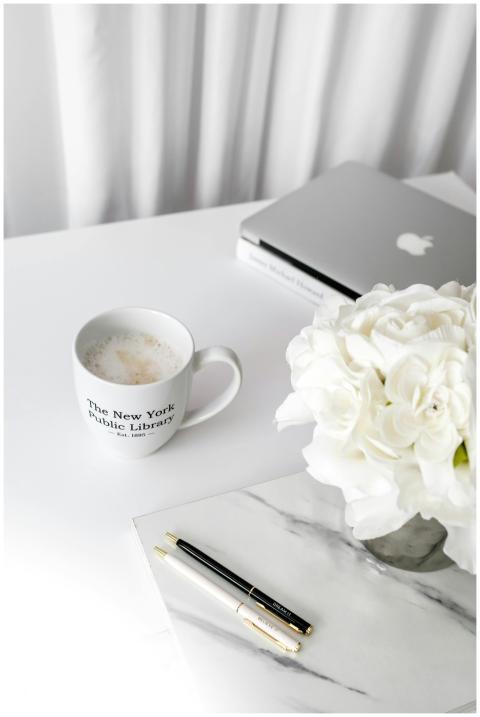 A clean desktop setup featuring a laptop, coffee m