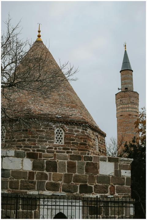 A historic brick building with a conical roof and
