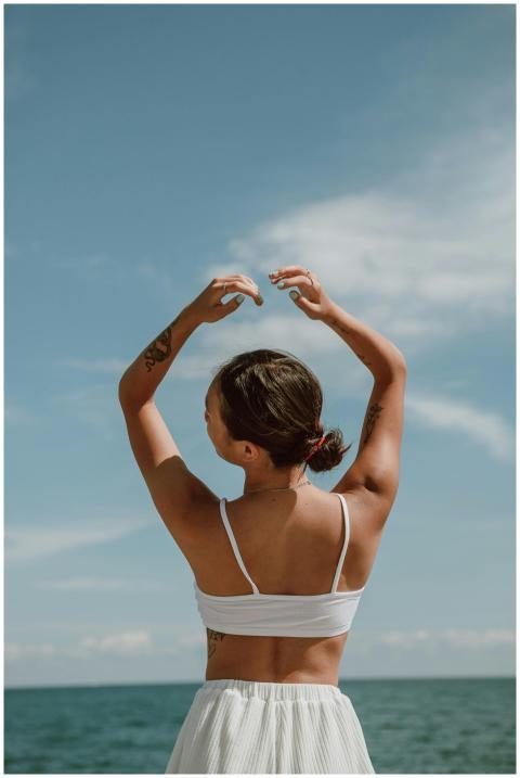 A woman raises her arms freely under the bright su