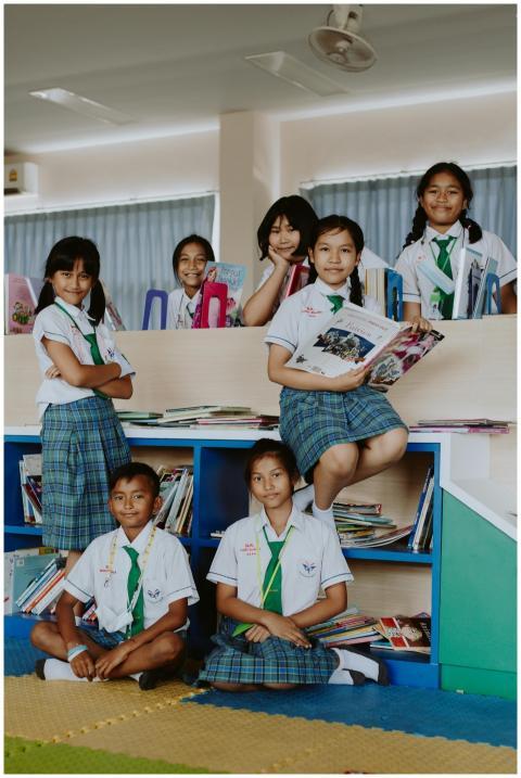 Group of children in school uniforms reading books